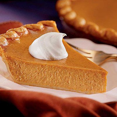A slice of pumpkin pie with whipped cream on top.