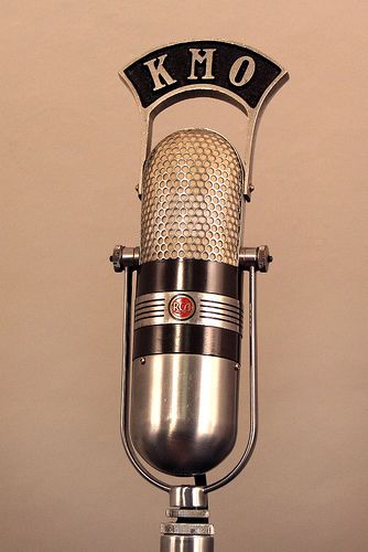 A vintage capsule-shaped RCA microphone topped with the letters KMO