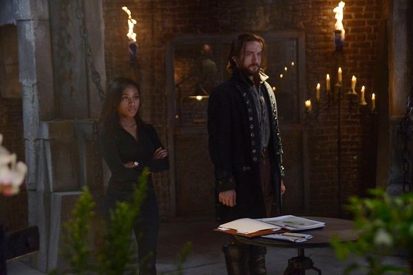 Abbie and Ichabod stand in front of a table with old paper sin a room of burning candles photo SHseason2ep1pr2_zps92d2a0c0.jpg