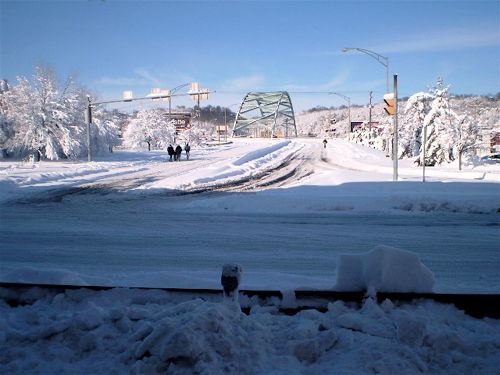 Pittsburgh's Birmingham Bridge surrounded by snow with three pedestrians